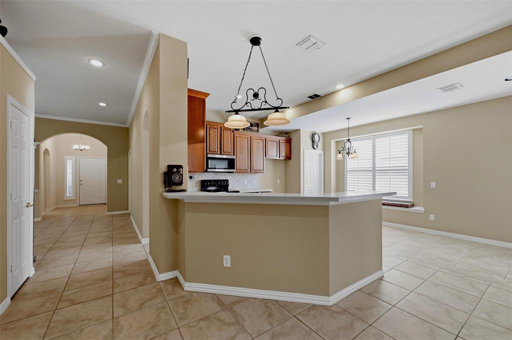 Kitchen featuring raised-panel wood cabinetry, a breakfast bar with stone-finish countertop, tile flooring, recessed lighting, and a decorative wrought iron pendant fixture
