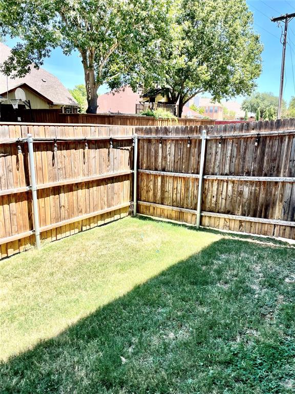 Fenced backyard featuring wood-plank perimeter fencing with metal posts and attached string lighting