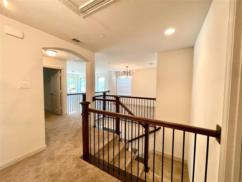 Staircase featuring dark wood handrails with metal balusters, arched architectural detail, recessed lighting, and wall-to-wall carpeting