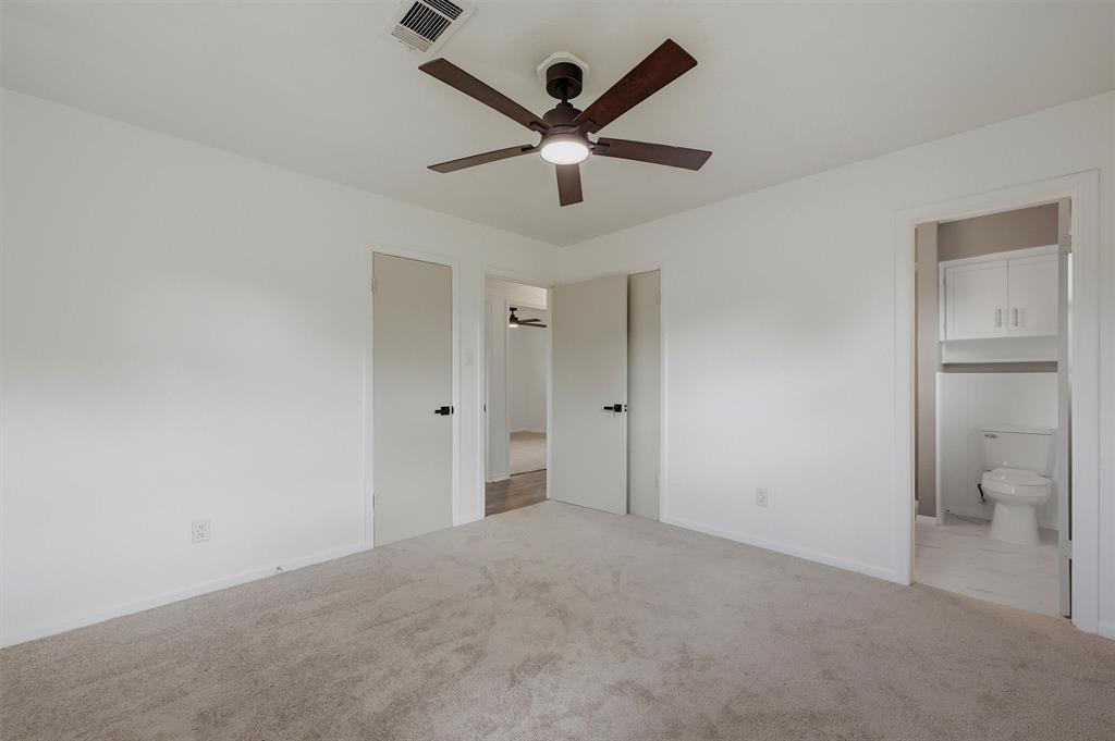 Neutral-toned carpeting, ceiling fan with integrated lighting, and multiple interior doors with matte black hardware