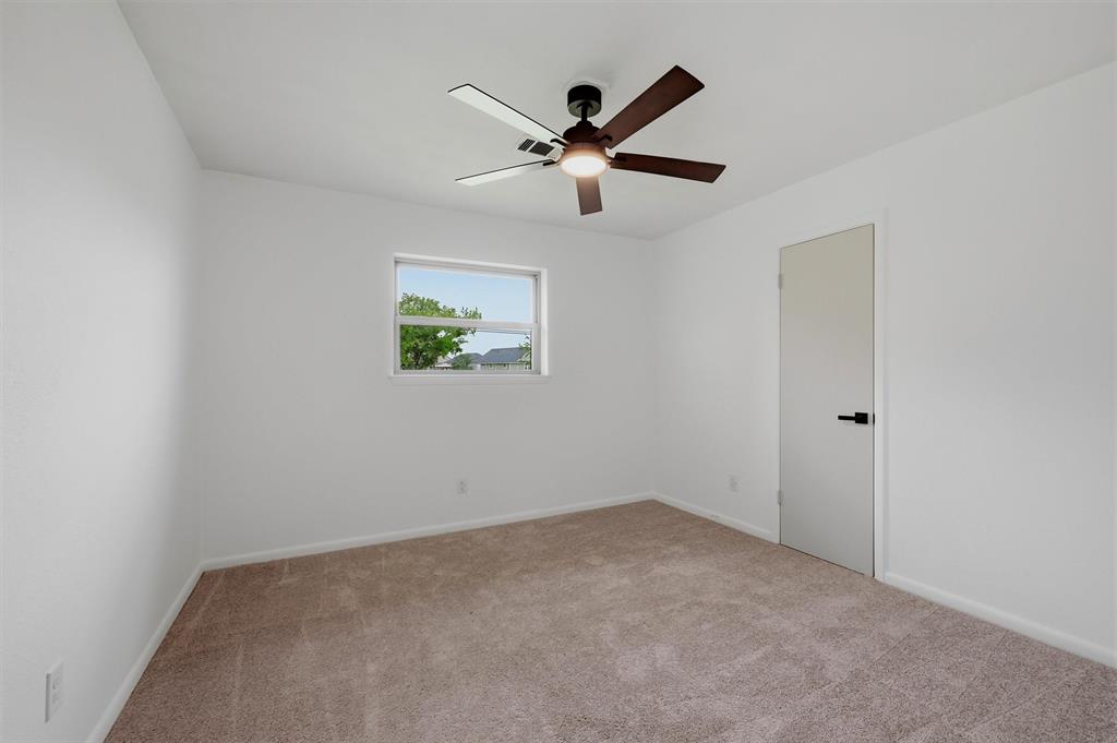 Neutral-toned carpeting, matte black door hardware, and a ceiling fan with integrated lighting