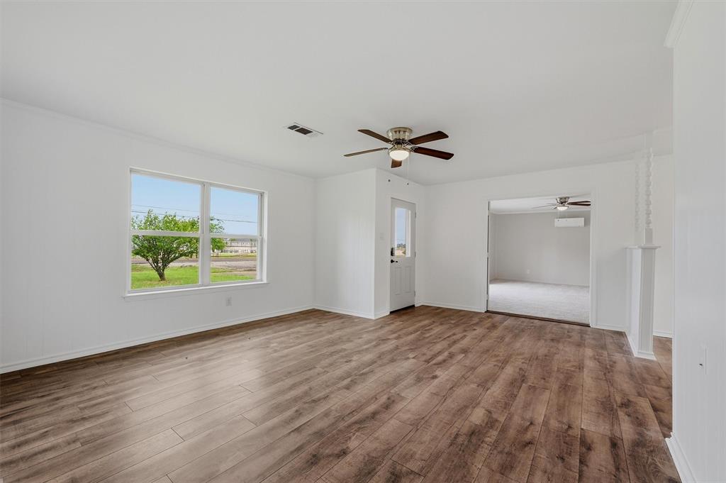 Open-concept interior featuring wood-finish flooring, a ceiling fan, and large windows with natural light Open-concept interior featuring wood-finish flooring, a ceiling fan, and large windows with natural light