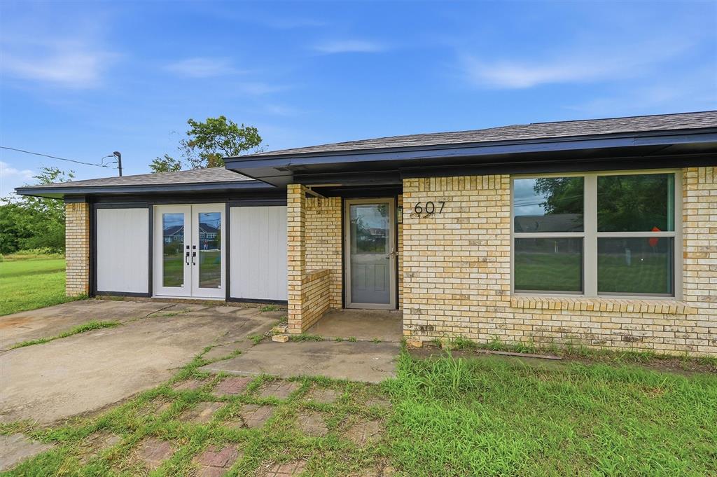 Single-story exterior featuring light-toned brick masonry, a low-pitch roofline, double glass-pane entry doors, and large windows Single-story exterior featuring light-toned brick masonry, a low-pitch roofline, double glass-pane entry doors, and large windows