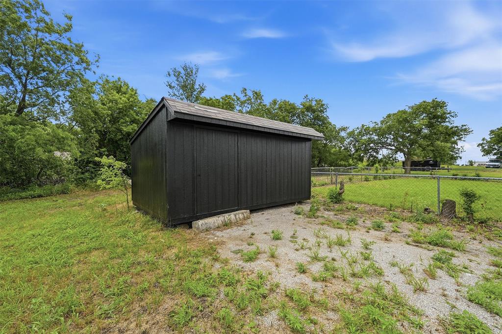 Black painted exterior storage structure featuring a pitched roof, vertical siding, and a gravel pad foundation