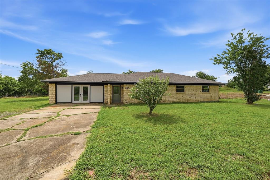 Single-story brick exterior featuring a hip roof, dual-pane white-framed doors, and an expansive lawn Single-story brick exterior featuring a hip roof, dual-pane white-framed doors, and an expansive lawn