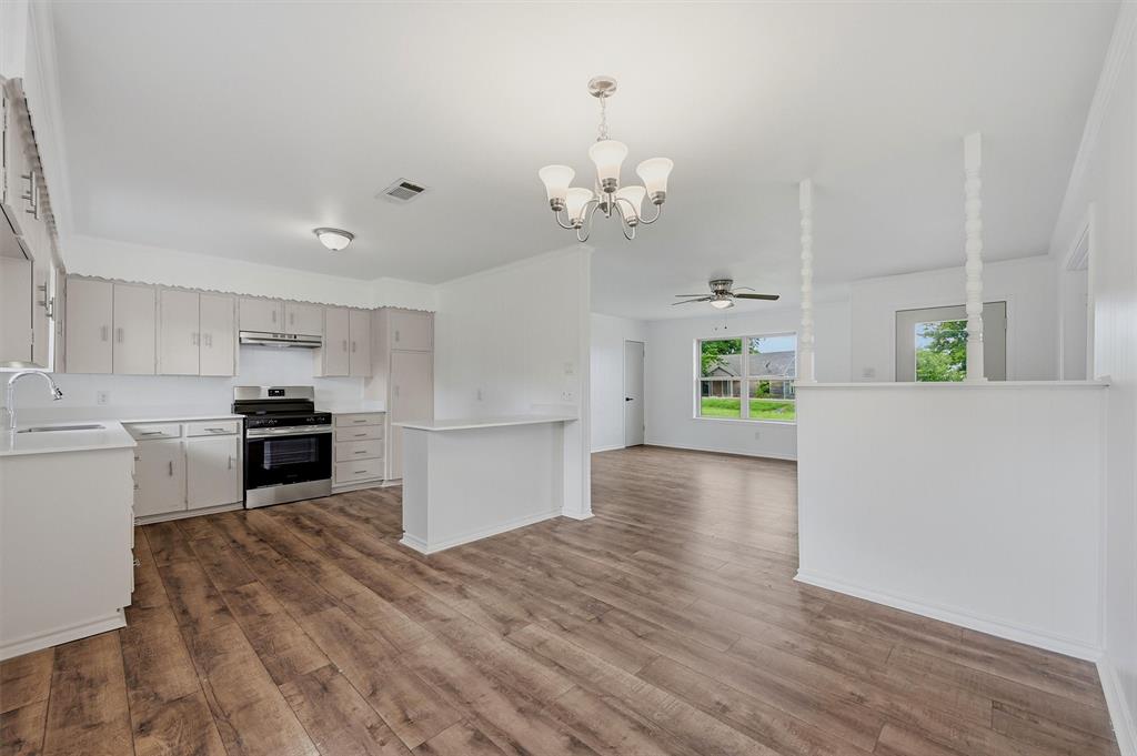 Kitchen featuring wood-finish flooring, white cabinetry, a stainless steel range, a peninsula, and a multi-light chandelier