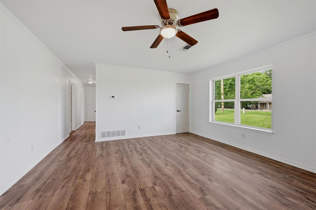 Interior space featuring wood-finish flooring, a ceiling fan with integrated lighting, neutral wall finishes, and a window with white trim Interior space featuring wood-finish flooring, a ceiling fan with integrated lighting, neutral wall finishes, and a window with white trim