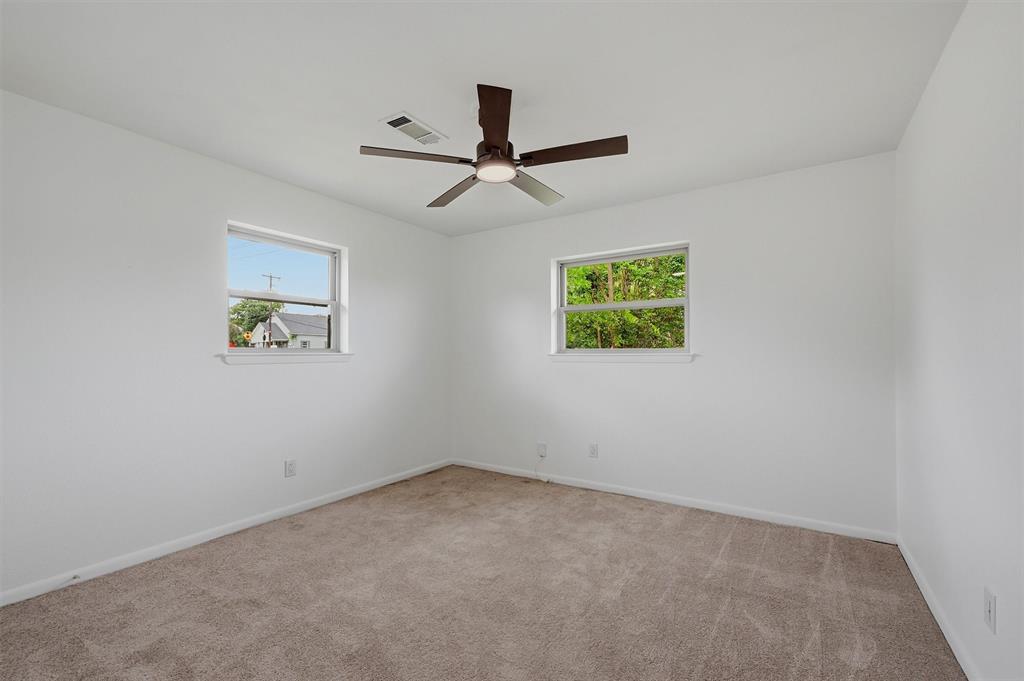 Neutral-toned carpeting, dual windows, and a central ceiling fan with integrated lighting