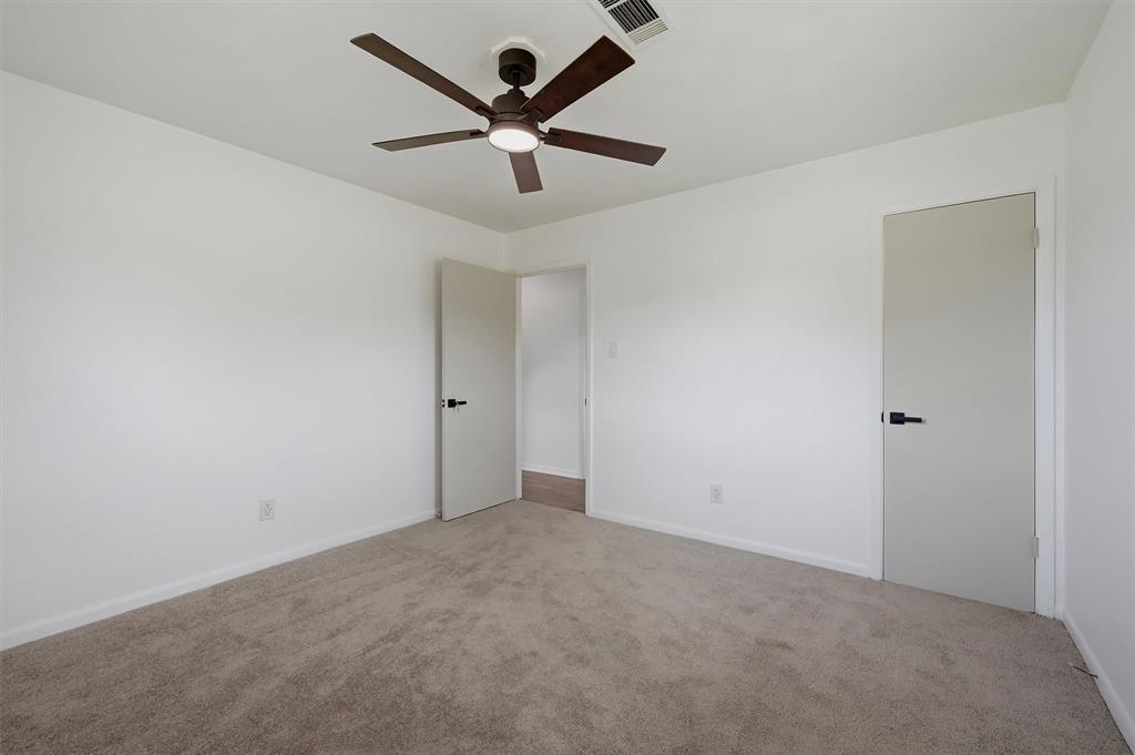 Neutral-toned carpeted flooring, multi-blade ceiling fan with integrated lighting, and doors featuring matte black hardware