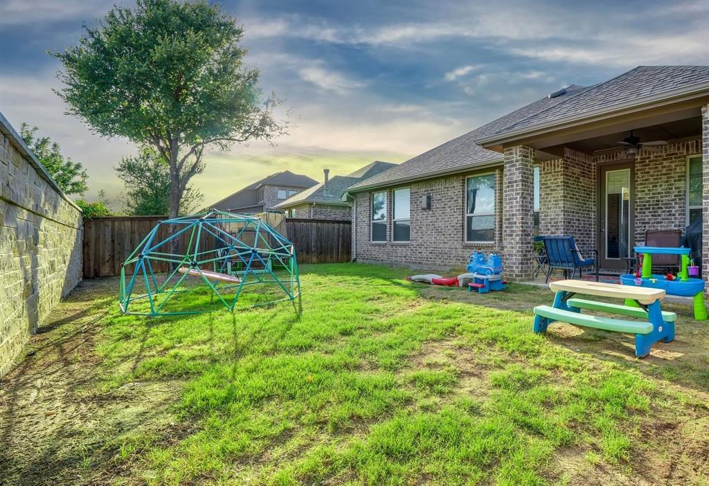 Backyard featuring a covered patio, brick exterior wall, masonry perimeter fencing, and mature trees