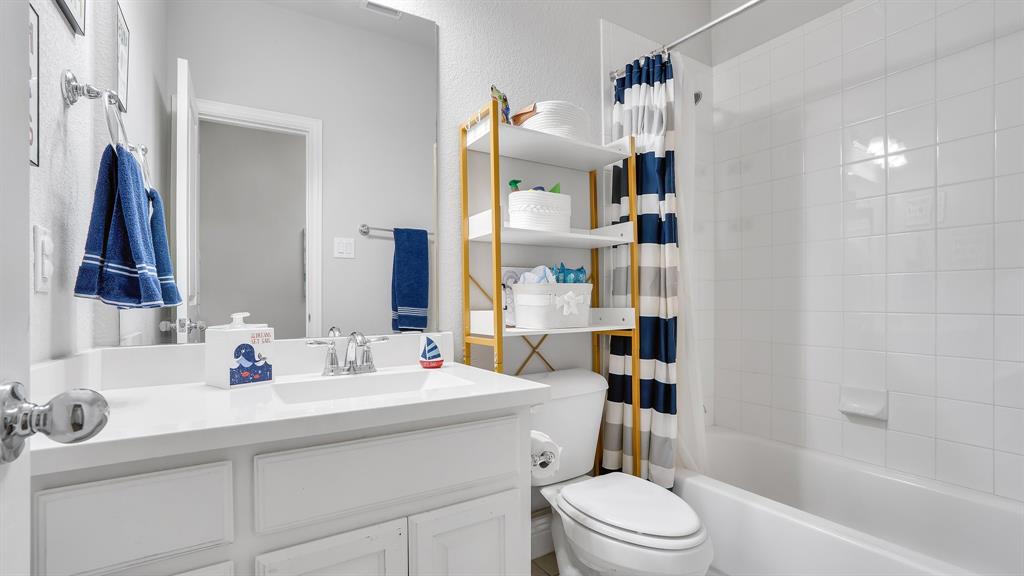 Bathroom featuring a white vanity with an integrated sink, polished chrome faucet, full-width mirror, and a tile-surround tub