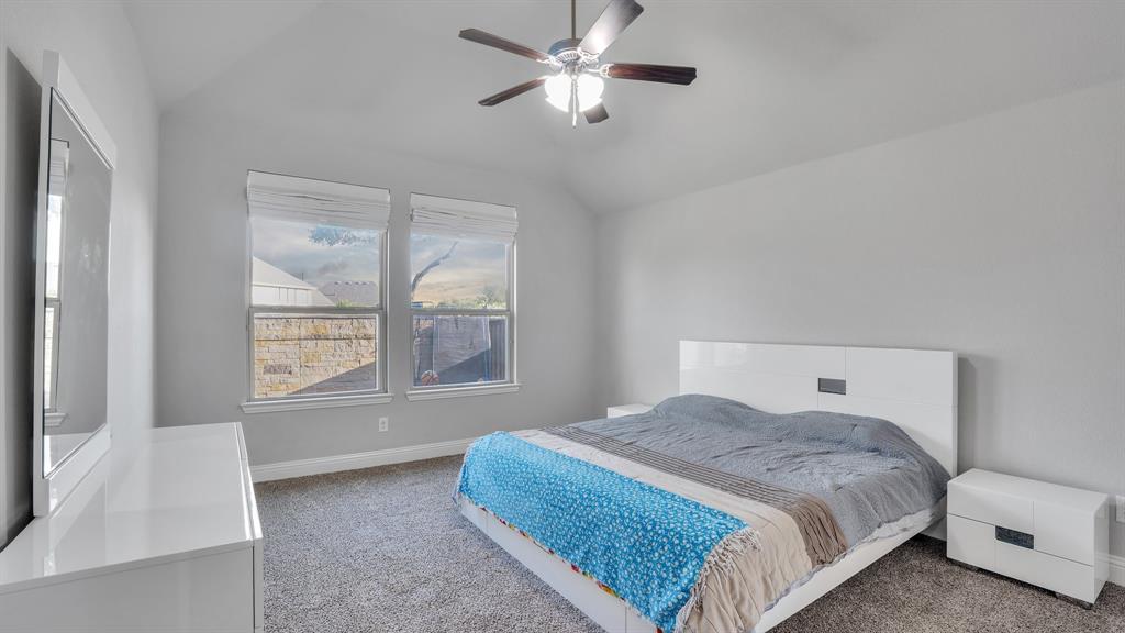 Vaulted ceiling, neutral wall tones, carpeted flooring, and a ceiling fan with integrated lighting Vaulted ceiling, neutral wall tones, carpeted flooring, and a ceiling fan with integrated lighting