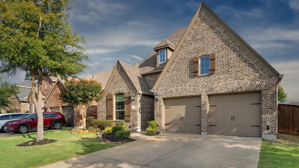 Brick exterior with multiple gables, arch-top windows, decorative wood shutters, and an attached two-car garage
