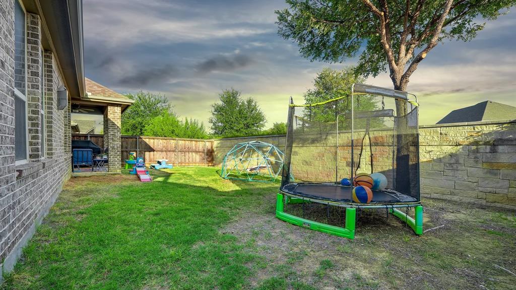 Backyard featuring brick exterior walls, a covered patio, a stone retaining wall, and wood-panel fencing