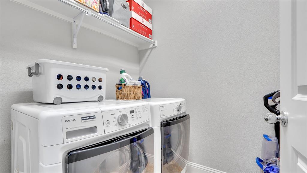 Laundry area featuring white appliances and wall-mounted wire shelving