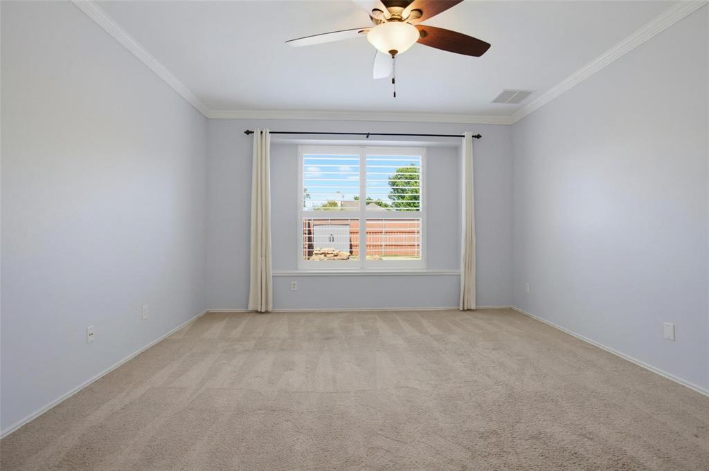 Spacious interior featuring neutral carpeting, crown molding, a ceiling fan with integrated lighting, and a window with plantation shutters