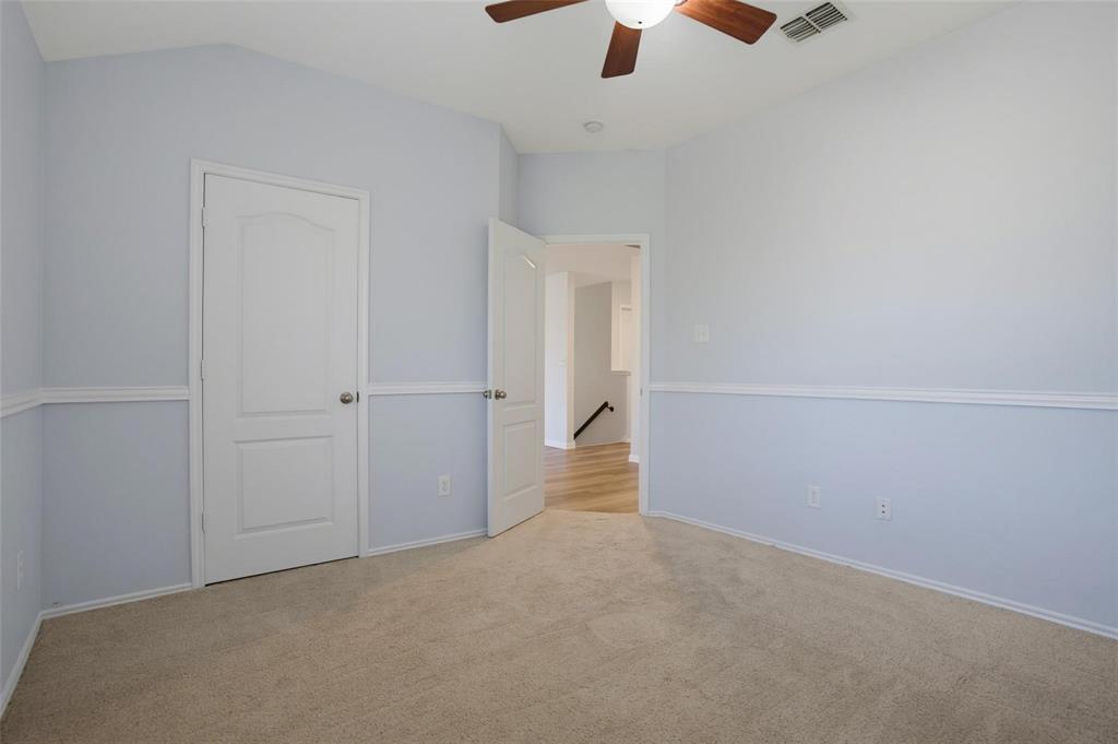 Vaulted ceilings, neutral carpeting, chair rail molding, solid-core interior doors, and a ceiling fan with integrated lighting