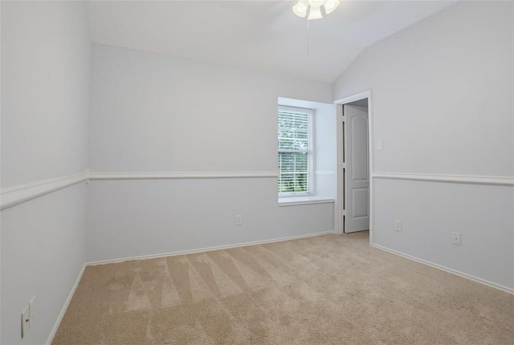 Vaulted ceiling with an integrated light fixture, neutral wall-to-wall carpeting, white chair rail molding, and a built-in window seat
