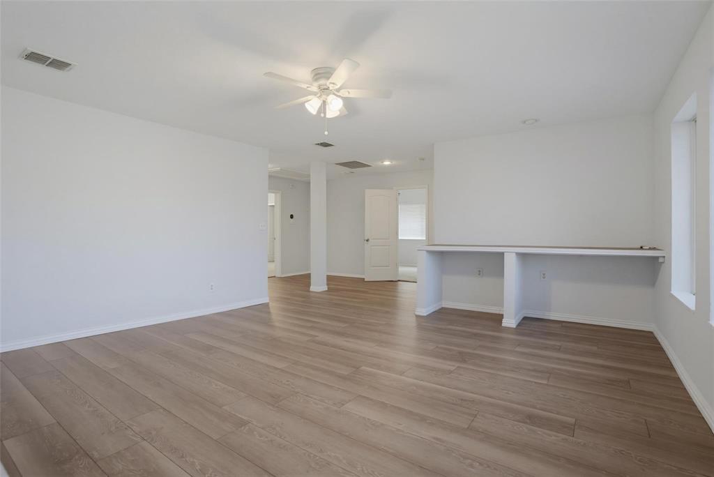 Open-concept room featuring wood-finish flooring, a white ceiling fan with integrated lighting, recessed lighting, and a built-in counter surface Open-concept room featuring wood-finish flooring, a white ceiling fan with integrated lighting, recessed lighting, and a built-in counter surface