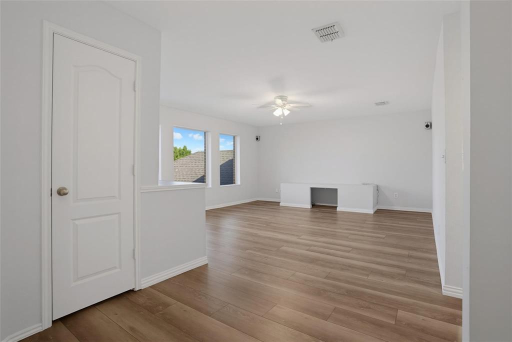 Interior space featuring wood-finish flooring, a neutral color palette, dual windows, a ceiling fan with integrated lighting, and built-in cabinetry Interior space featuring wood-finish flooring, a neutral color palette, dual windows, a ceiling fan with integrated lighting, and built-in cabinetry