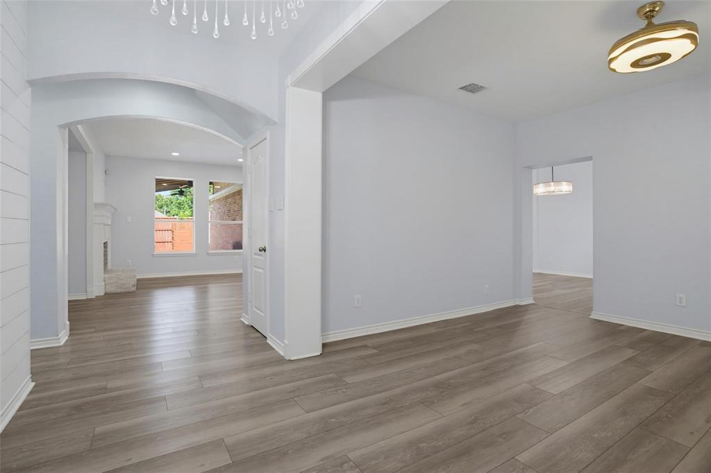 Architectural archways, wood-finish flooring, recessed lighting, and multi-tier pendant fixtures