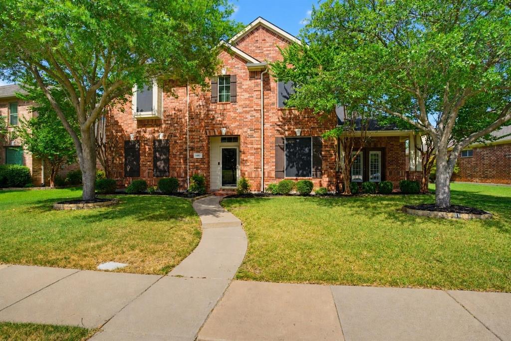 Two-story brick exterior featuring dark window shutters, a front entryway with a transom window, and a concrete walkway