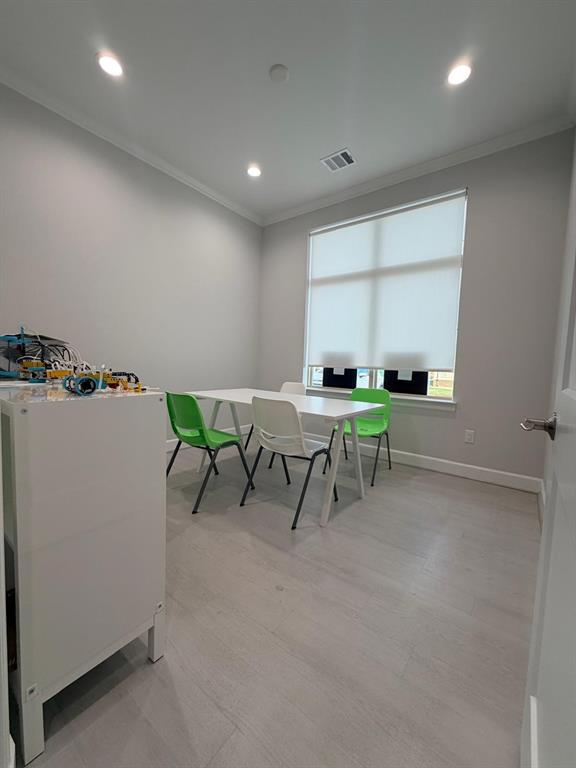 Interior room featuring light wood-finish flooring, recessed lighting, neutral wall paint, and a large window with a roller shade