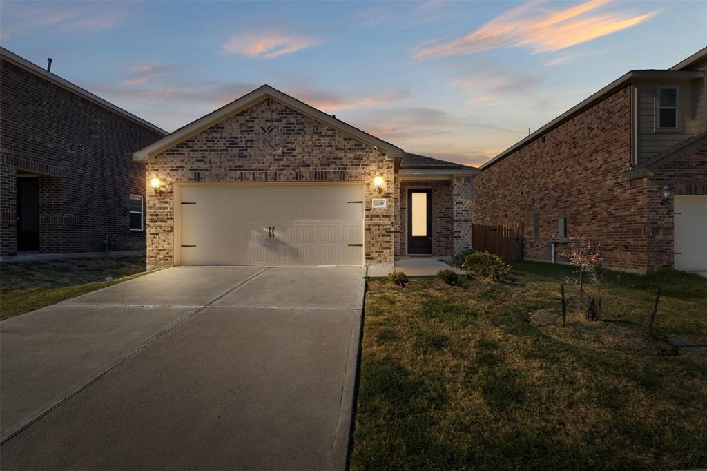 Single-story residence featuring a multi-toned brick facade, gabled roofline, concrete driveway, and a two-car garage with decorative hardware
