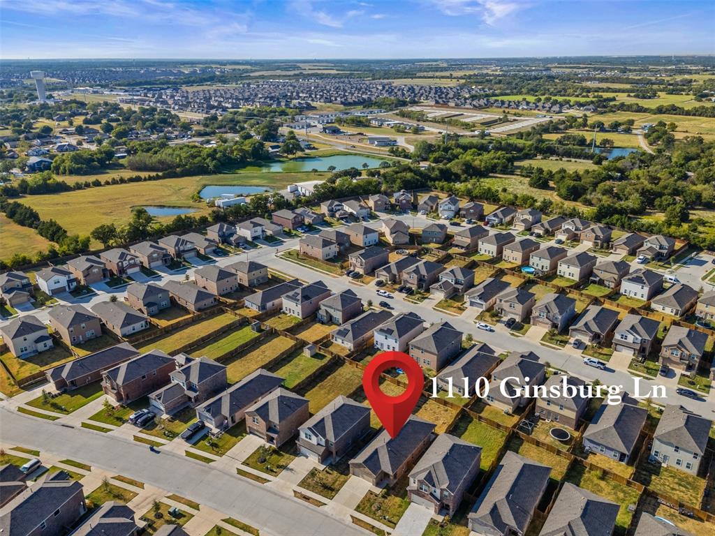 Aerial perspective of a residential property featuring a paved driveway, a multi-pitched roofline, and a private rear lawn