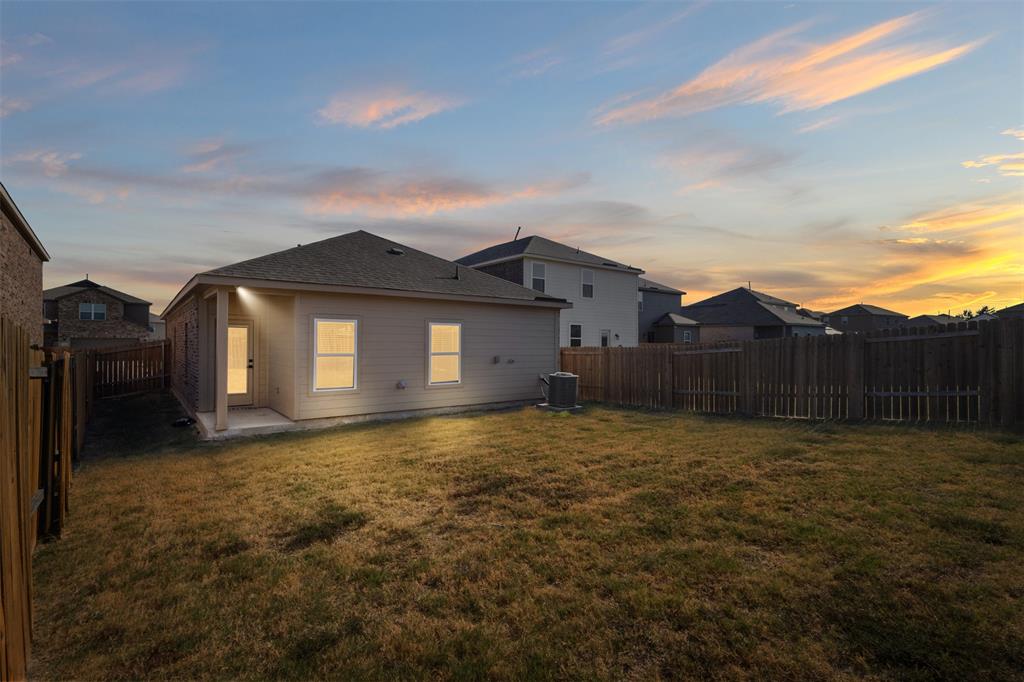 Rear exterior featuring neutral-toned siding, a covered patio area, and a privacy wood fence