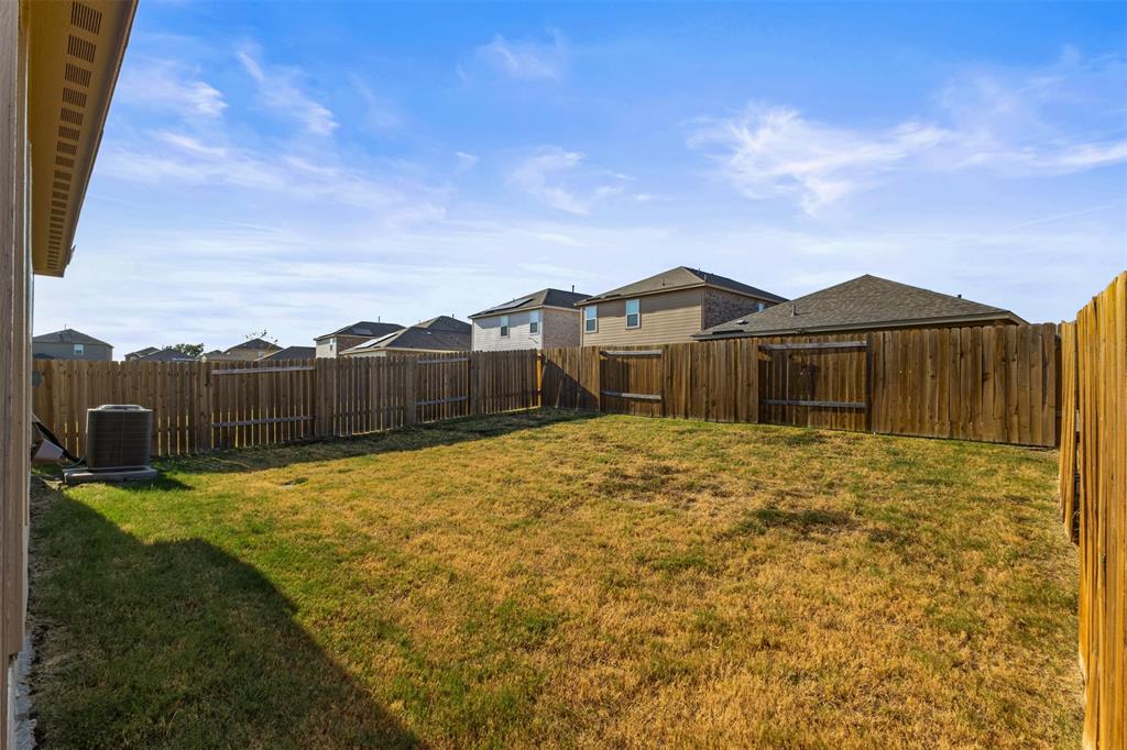 Backyard featuring a grass lawn, perimeter wood fencing, and an exterior HVAC unit