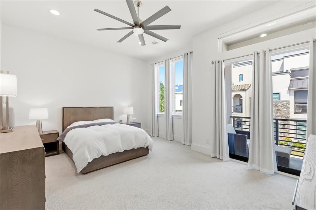 High-ceiling bedroom featuring recessed lighting, a multi-blade ceiling fan, expansive windows, and a sliding glass door providing external balcony access