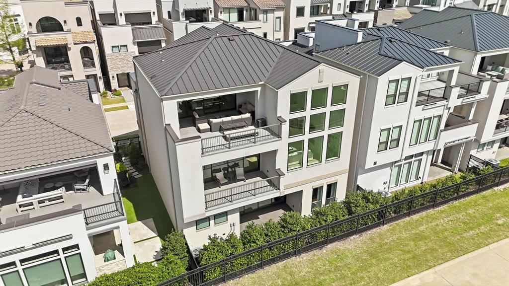 Multi-level exterior featuring a metal roof, stacked balconies with metal railings, and oversized floor-to-ceiling windows