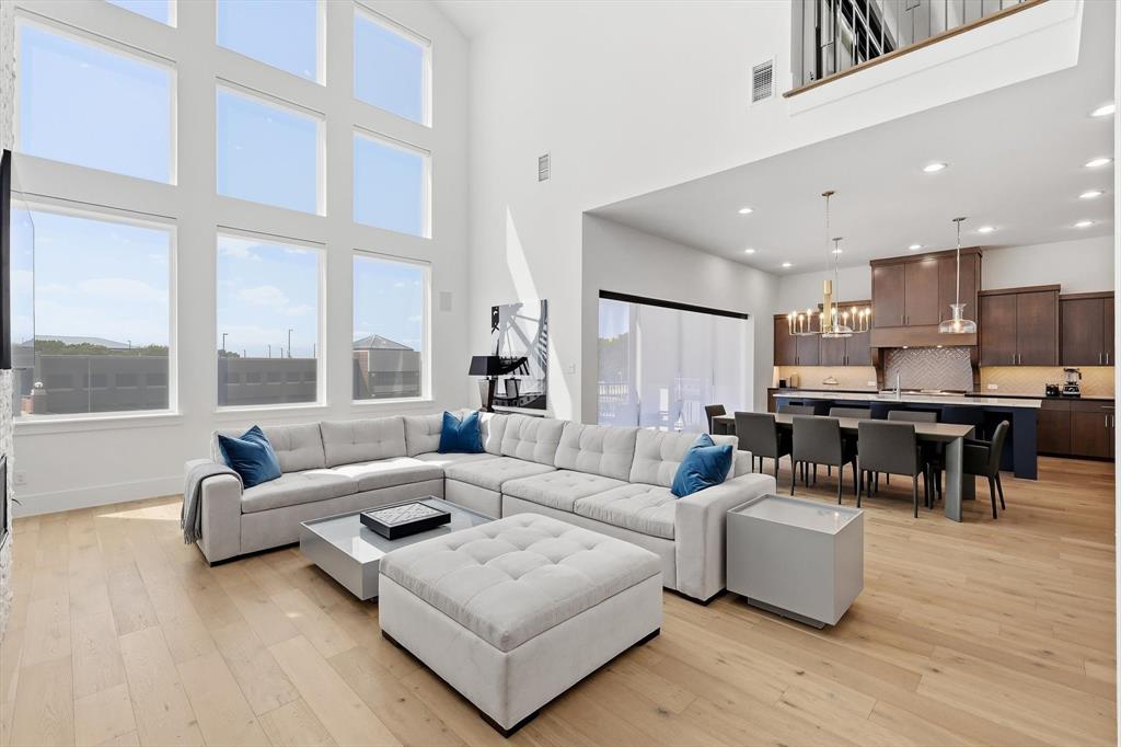 Double-height ceilings with floor-to-ceiling windows, wood-finish flooring, custom wood cabinetry, and recessed lighting Double-height ceilings with floor-to-ceiling windows, wood-finish flooring, custom wood cabinetry, and recessed lighting
