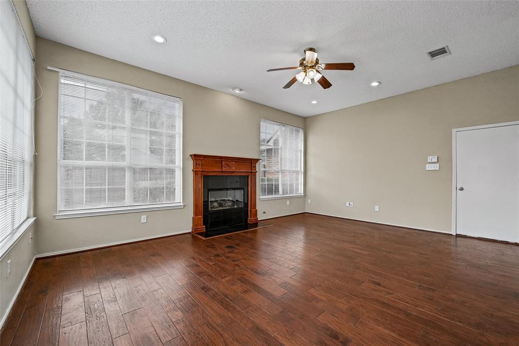 Living space featuring wood-finish flooring, a fireplace with a decorative wood mantel, multiple large windows, and recessed lighting