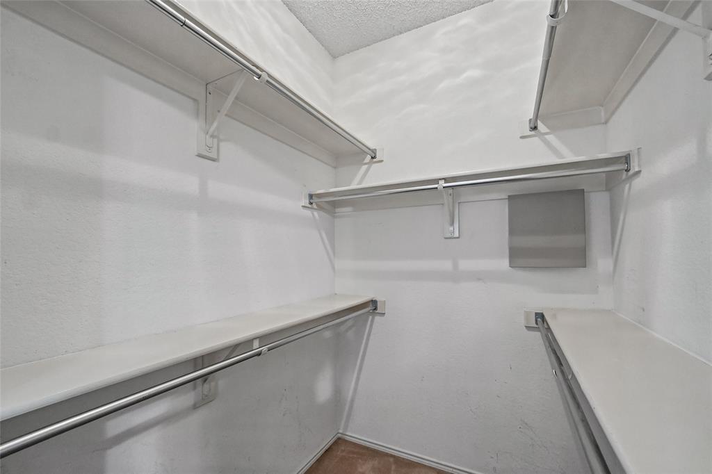 Walk-in closet featuring multi-level shelving, integrated metal hanging rods, and neutral interior finishes