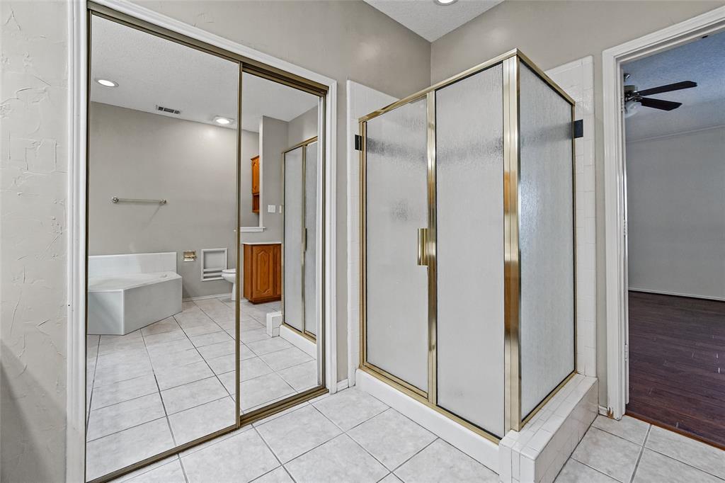 Bathroom featuring a glass-enclosed shower, mirrored sliding closet doors, built-in soaking tub, tiled flooring, and recessed lighting