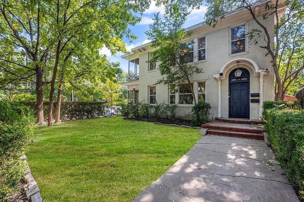 Two-story painted brick exterior featuring an arched entryway, decorative molding, multi-pane windows, and a screened porch