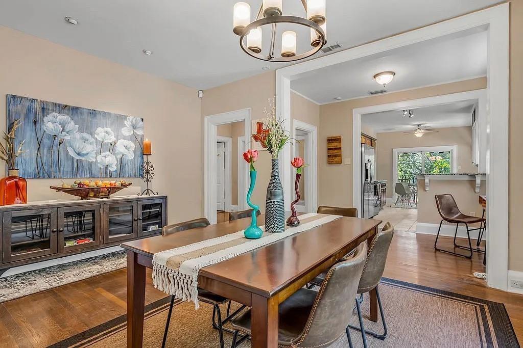 Dining area featuring wood-finish flooring, a contemporary six-light circular chandelier, and built-in cabinetry with glass-front doors