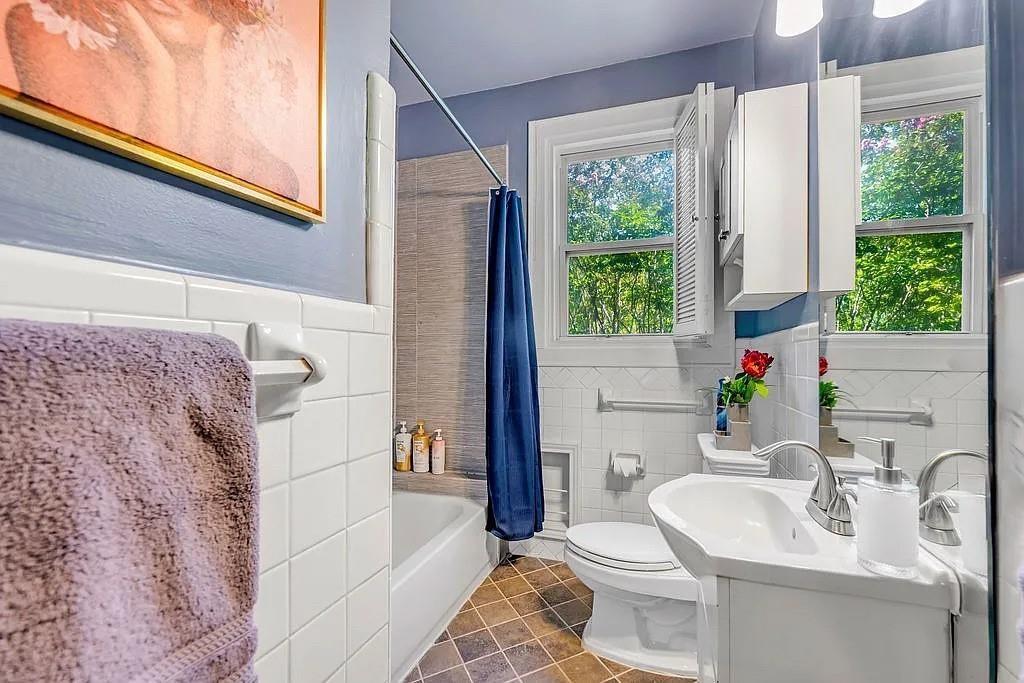 Bathroom featuring white subway tile wall surrounds, a pedestal sink with a dual-handle faucet, a built-in medicine cabinet, and a bathtub with a tiled enclosure