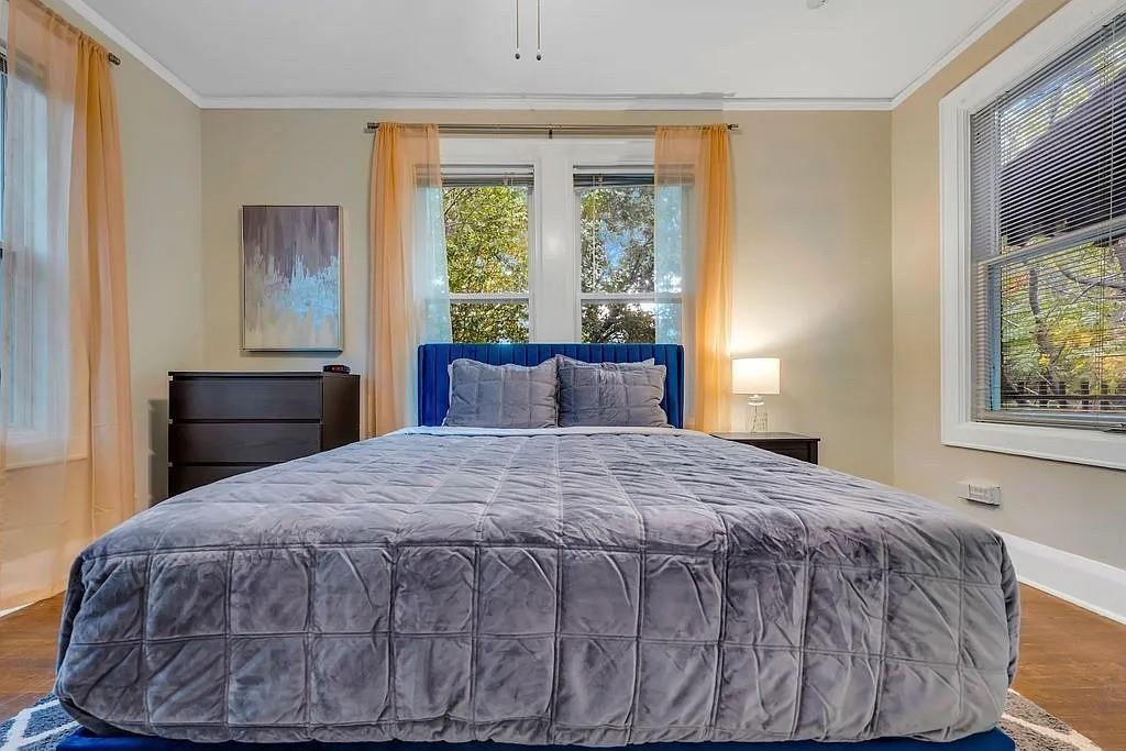 Room featuring wood-finish flooring, multiple windows with white trim, and a ceiling-mounted light fixture