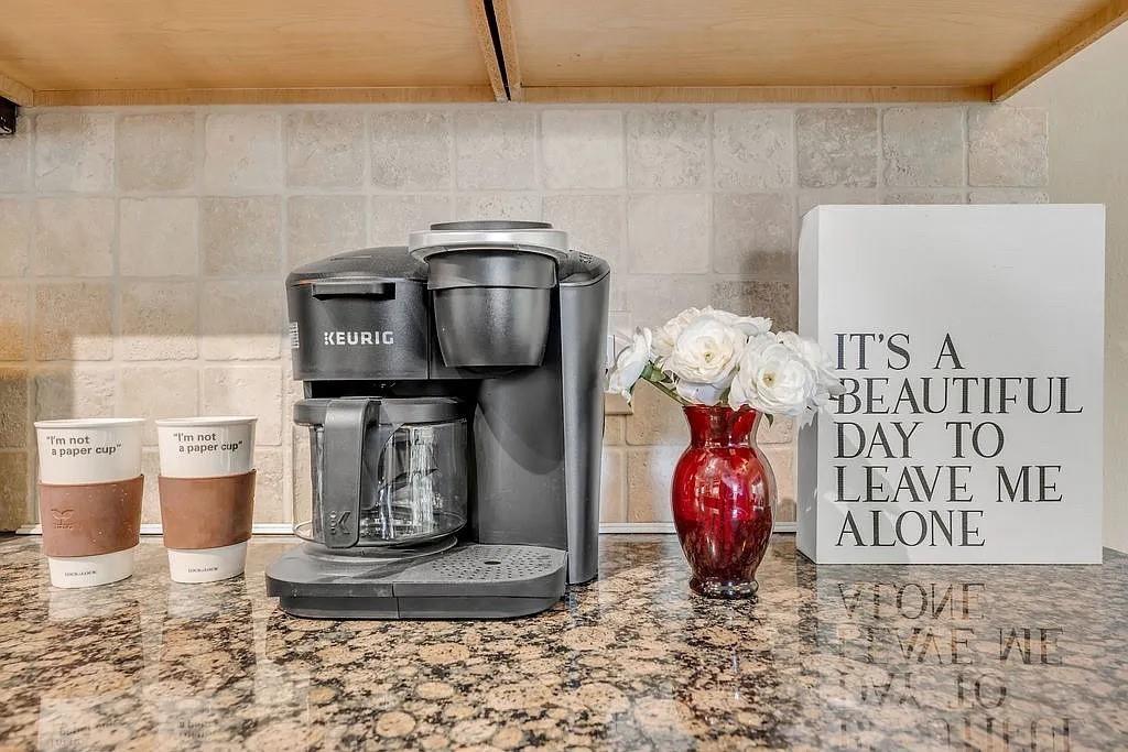 Natural stone countertop featuring a polished finish, paired with a neutral-toned square tile backsplash and upper wood cabinetry