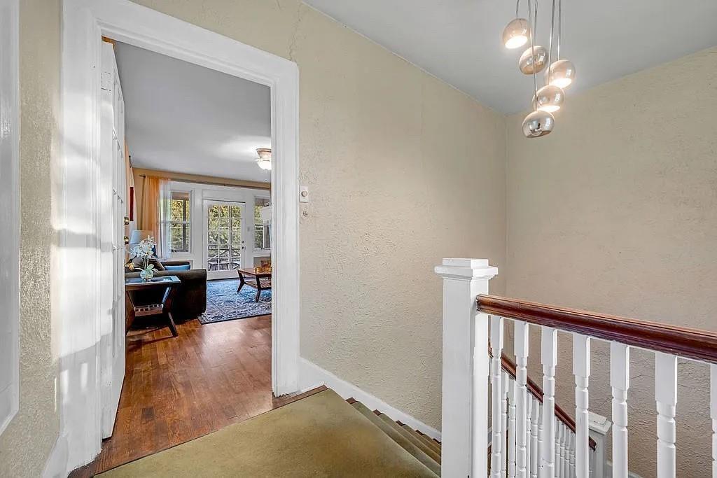 Staircase featuring a white wooden balustrade with a dark wood handrail, polished multi-globe pendant lighting, and wood-finish flooring