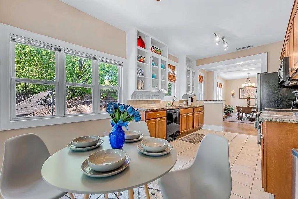 Kitchen featuring wood cabinetry, stone countertops, integrated white glass-front cabinetry, tile flooring, and oversized windows