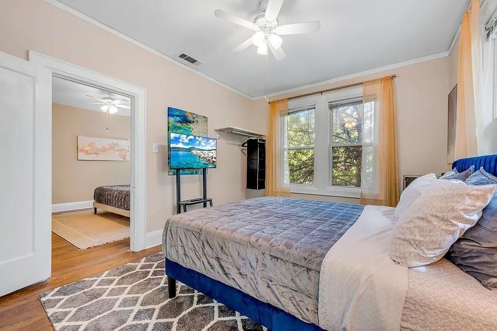 Room featuring wood-finish flooring, dual-pane windows, and a ceiling-mounted light fixture with fan