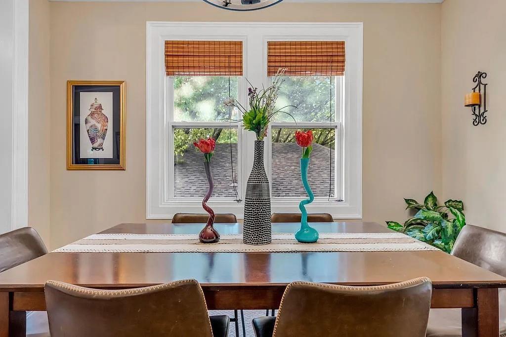 Double-hung window with white millwork casing, woven wood shades, and a decorative wall-mounted metal sconce Double-hung window with white millwork casing, woven wood shades, and a decorative wall-mounted metal sconce