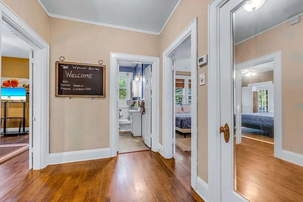 Interior hallway featuring wood-finish flooring, white door casing, and a full-length mirrored door