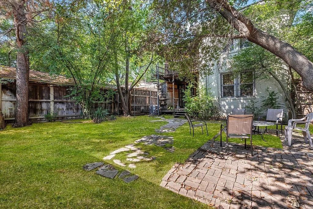 Backyard featuring a paver patio, stone path, wood perimeter fencing, and mature trees