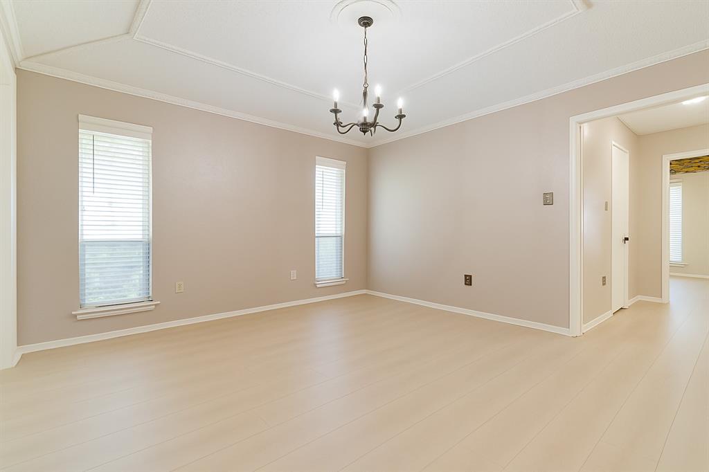 Primary bedroom with light wood-type flooring, a chandelier, crown molding, and baseboards