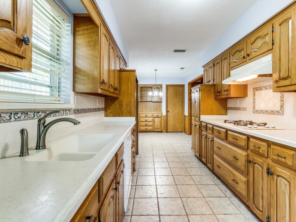 Kitchen featuring a sink, under cabinet range hood, decorative backsplash, white appliances, and light countertops